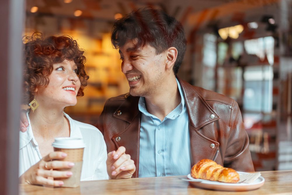 Two people smiling over coffee in a café
